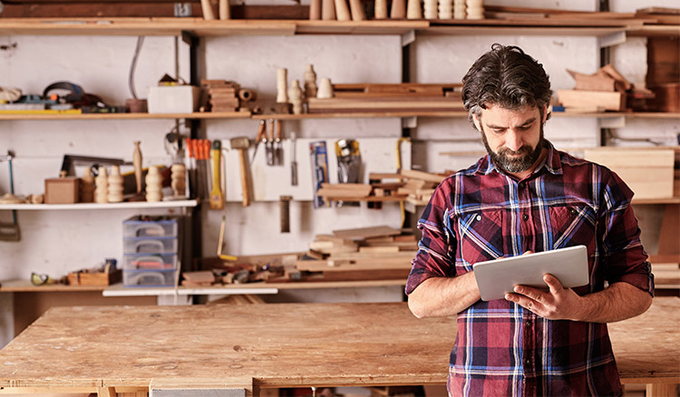 Caucasian Male Business Owner Using Tablet In Workshop