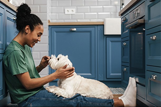 african american woman in kitchen with puppy